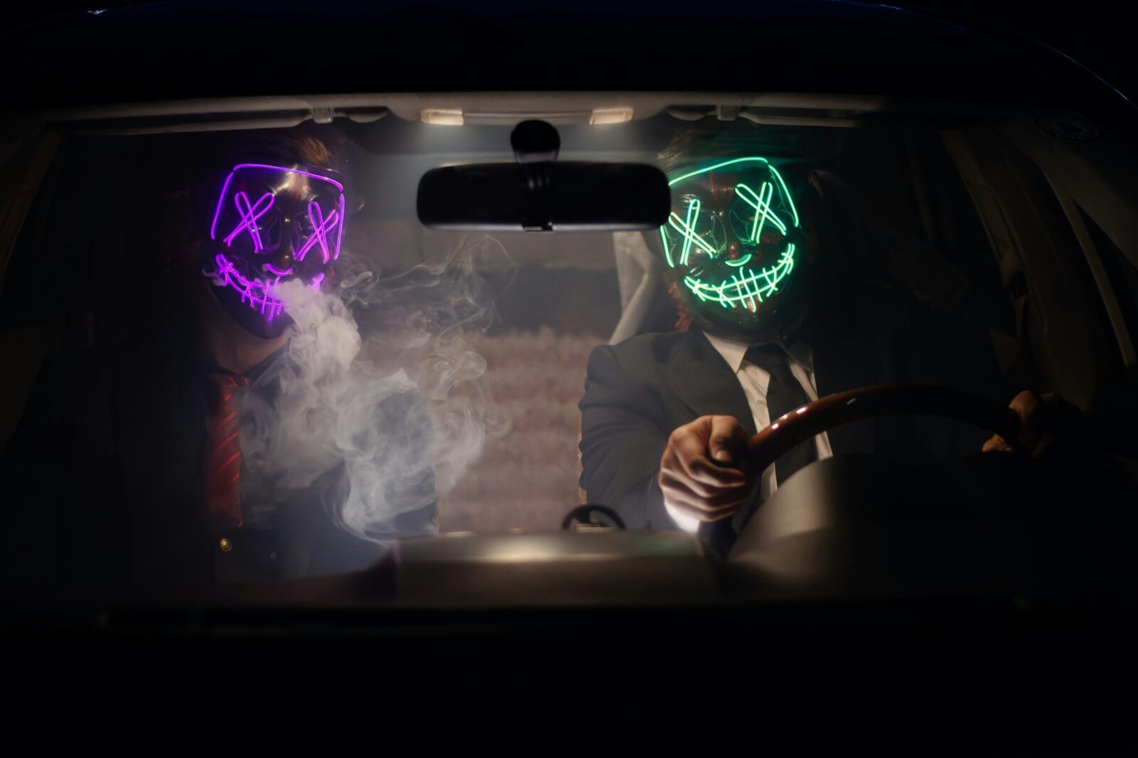 Two people in a car wearing illuminated skull masks.